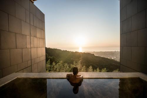 une personne assise dans une piscine et vue sur le coucher du soleil dans l'établissement ANA InterContinental Beppu Resort & Spa, an IHG Hotel, à Beppu