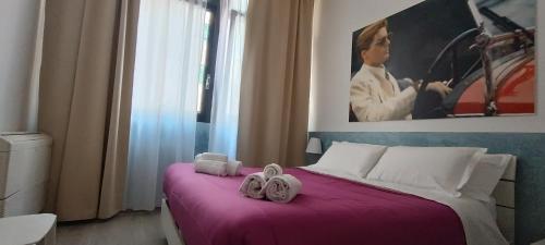 una camera da letto con un letto viola e due asciugamani di Dimora Santa Barbara a Ferrara