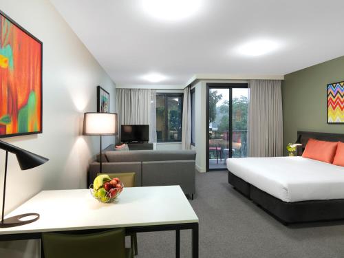 a hotel room with a bed and a couch at Adina Apartment Hotel Sydney Airport in Sydney