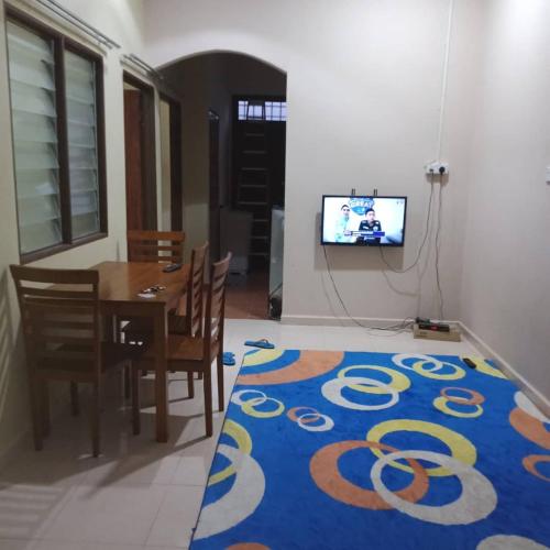a dining room with a table and a blue rug at Sobey Laris Homestay AZANA in Pasir Mas