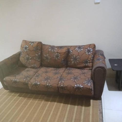 a brown couch sitting on top of a rug at Sobey Laris Homestay AZANA in Pasir Mas