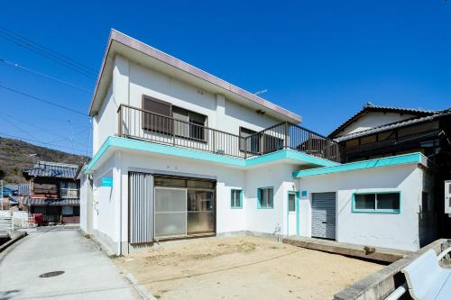 une maison blanche avec un balcon dans une rue dans l'établissement 島のまくら, à Kure