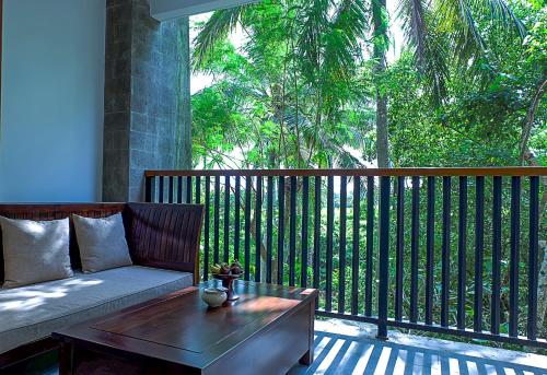 a porch with a couch and a coffee table at Visesa Ubud Resort in Ubud