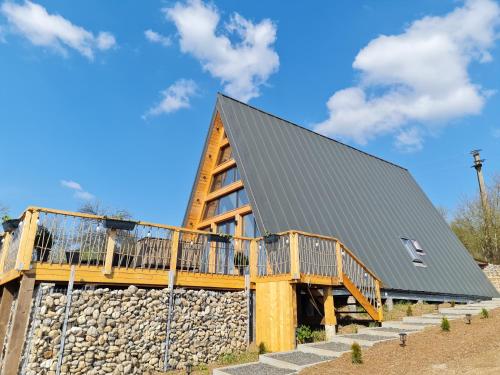 a log cabin with a stone wall and a gray roof at Cabanele A Frame, Salciua Noua in Sălciua Nouă