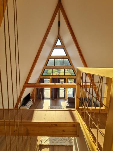 a loft with a large window in a room at Cabanele A Frame, Salciua Noua in Sălciua Nouă