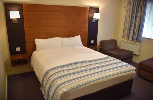 um quarto de hotel com uma cama grande e uma cadeira em Eyesleepover em Eyemouth
