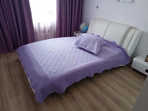 a bed with a purple blanket on top of it at Cozy Popesti in Popeşti-Leordeni