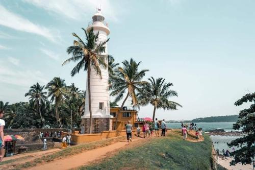a lighthouse on the beach with people walking around it at DiNi Galle in Galle