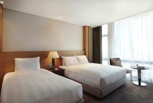 a hotel room with two beds and a window at Lotte City Hotel Jeju Airport in Jeju