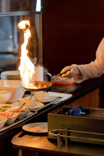a person cooking food in a kitchen with flames at Wellborn Luxury Hotel in Kocaeli