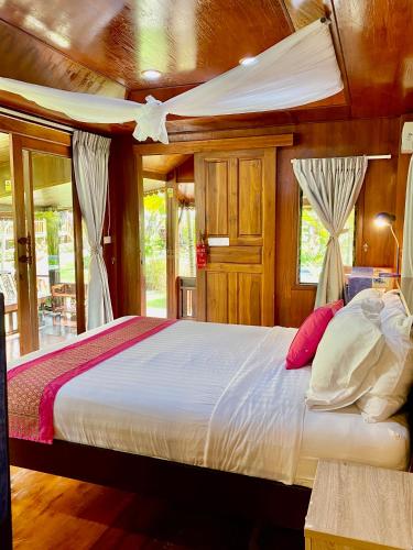 a bedroom with a large bed with wooden walls and windows at Thai House Resort in Hua Hin