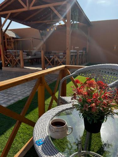 a table with a cup of coffee and flowers on a balcony at شاليه الخفجي in Al Khafji