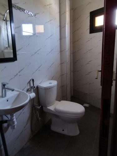 a bathroom with a white toilet and a sink at Ruhige, helle Wohnung beim Lac Rose in Dakar