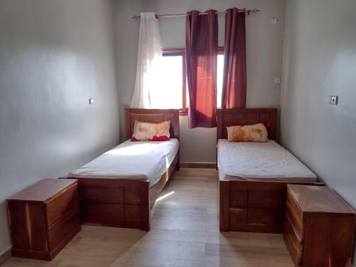 two beds in a room with a window at Ruhige, helle Wohnung beim Lac Rose in Dakar