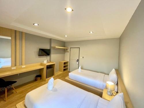 a hotel room with two beds and a desk at Klaang Muang Hotel (โรงแรมกลางเมือง) in Rayong
