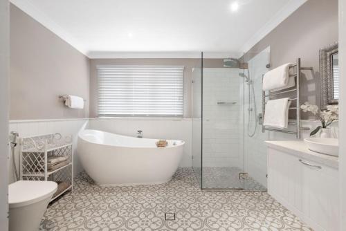 a bathroom with a tub and a toilet and a sink at Currawong in Blackheath
