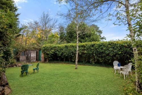 a yard with lawn chairs and a hedge at Currawong in Blackheath
