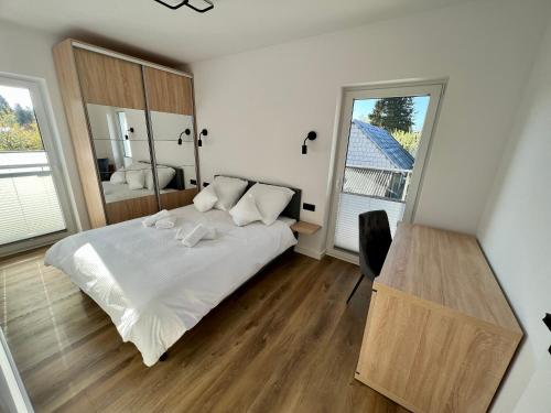 a bedroom with a bed and a desk and a window at Złoty Apartament in Tykocin