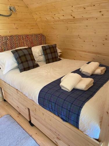 a bed in a wooden cabin with pillows on it at The Chestnuts Pod with private garden. 