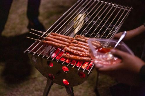 a person is cooking hot dogs on a grill at Bintan Exotica Resort By WH - Free Shuttle BBT Resort BBT - Free Breakfast in Berakit