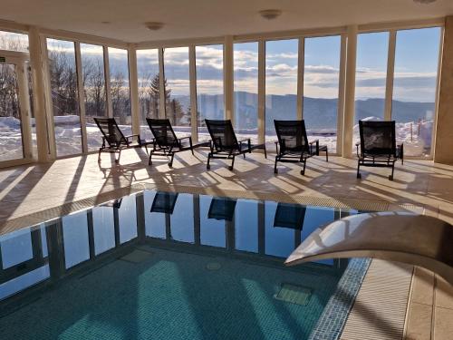 a swimming pool with chairs and a view of the mountains at Wellness Chata Jana in Lopeník