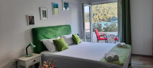 ein Schlafzimmer mit einem Bett mit grünem Kopfteil und einem Balkon in der Unterkunft Apartment Sea Dream in Ston