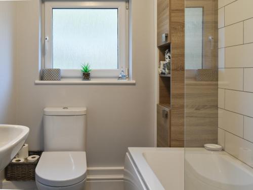 baño con aseo y lavabo y ventana en White Cottage, en Llandudno