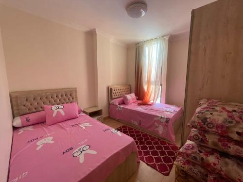 twee bedden in een kamer met roze lakens bij جراند هيلز الساحل الشمالي مدينه الحمام الكيلو 60 in Abû Zeira
