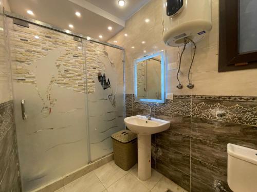 een badkamer met een wastafel en een glazen douche bij جراند هيلز الساحل الشمالي مدينه الحمام الكيلو 60 in Abû Zeira