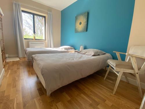 - 2 lits dans une chambre avec un mur bleu dans l'établissement Villa- Calme - Campagne - Bien être, à Saint-Grégoire