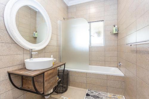 a bathroom with a sink and a tub and a mirror at Kruger Huisie Parys in Parys