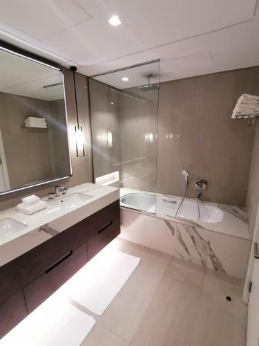 a bathroom with two sinks and a tub and a mirror at Three Bedroom Apartment at Address Residence Fujairah in Sharm
