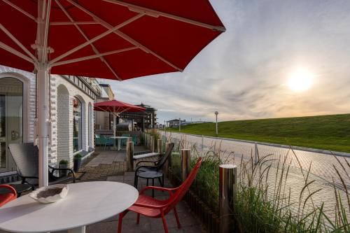 a patio with tables and chairs and an umbrella at Strandvilla an der Kaiserwiese in Norderney