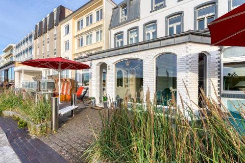 um edifício com um guarda-chuva vermelho em frente em Strandvilla an der Kaiserwiese em Norderney