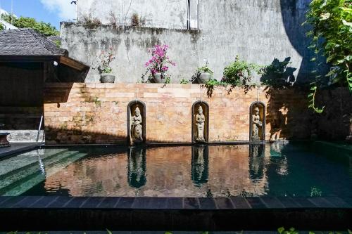 a swimming pool with some plants on the side of a building at Taman Ayu Legian Hotel in Legian