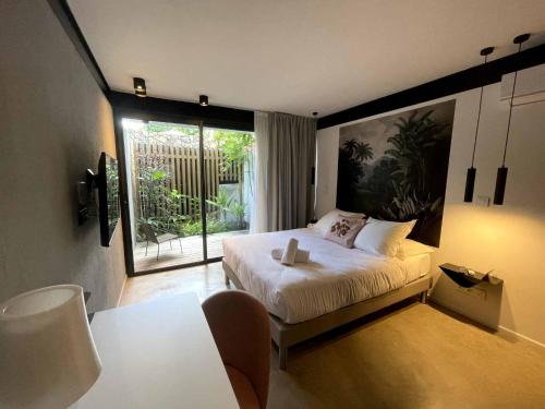 a bedroom with a bed and a large window at Clos de la Rivière in Saint-Denis