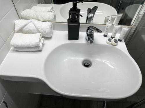 a white sink in a bathroom with towels at DCH on Mitchell in Darwin