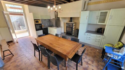 uma cozinha com uma mesa de madeira e cadeiras em Gite de la Fontaine em La Bazouge-des-Alleux