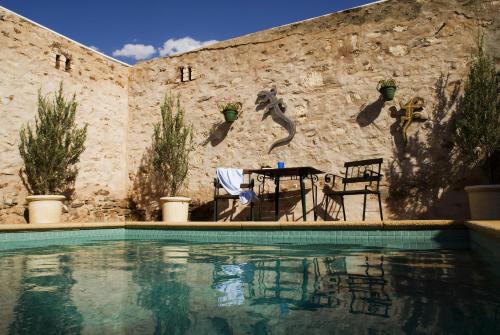 a swimming pool with a table and chairs next to a wall at Imperial Fine Accommodation in Broken Hill