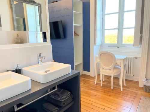 een badkamer met een wastafel en een tafel met een stoel bij Domaine du Plessis Grimaud in Saint-Viaud
