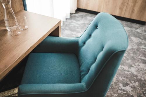 a blue chair sitting next to a wooden table at Hotel Schölzhorn Superior in Racines