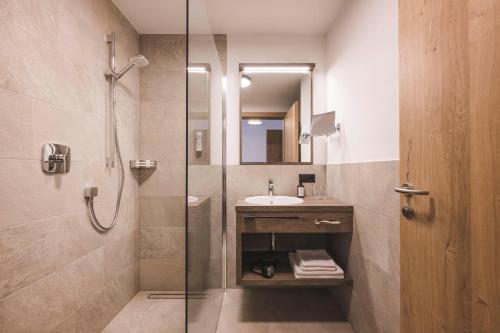 a bathroom with a glass shower and a sink at Hotel Schölzhorn Superior in Racines