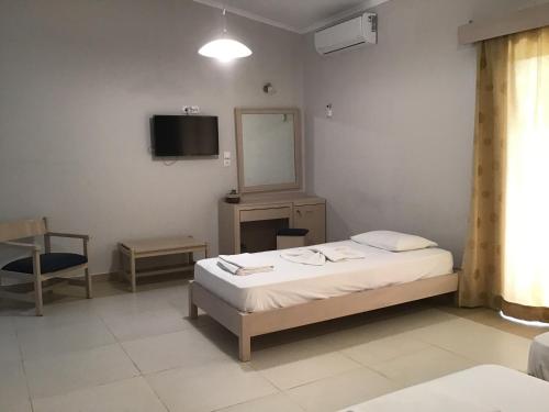 a bedroom with a bed and a mirror and a tv at Regina Hotel in Kissamos