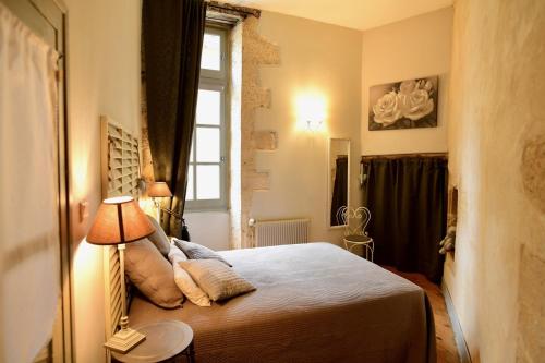 een slaapkamer met een bed met een lamp en een raam bij Truffle in Sarlat-la-Canéda