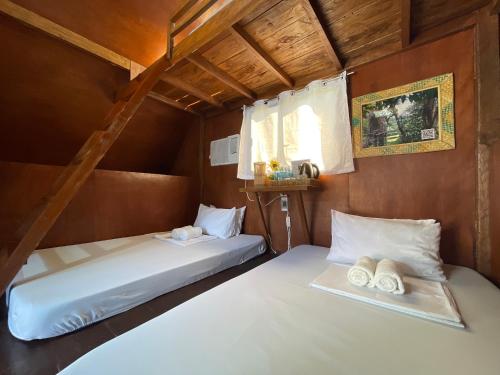 due letti in una piccola stanza con asciugamani sopra di La Vie Adventure Trails a Salabusob