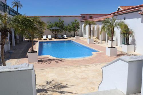 a swimming pool in a courtyard with palm trees at SOLAR DOS FRADES in Ferreira do Alentejo