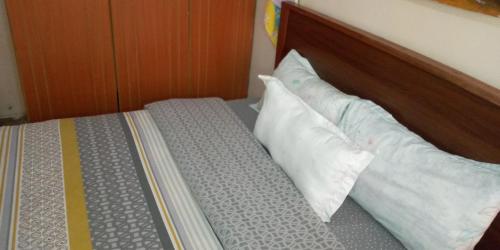a bed with two pillows and a wooden headboard at The Red Nest Nahashon Kimemia One Bedroom in Nairobi