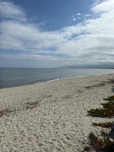 a sandy beach with the ocean on a cloudy day at Maison les pieds dans l’eau in Ghisonaccia