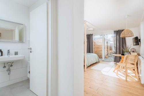 a white kitchen with a table and a bedroom at Apartments Kassebohmer Weg in Rostock