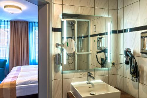 a bathroom with a sink and a room with a bed at Trip Inn City Hotel Giessen in Gießen